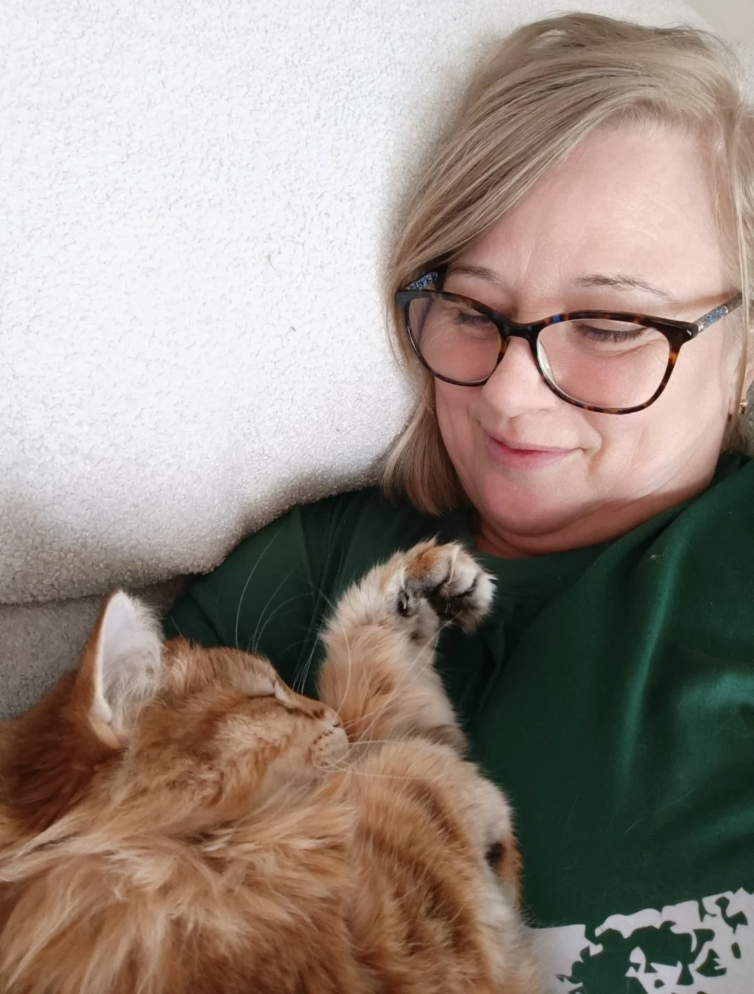Liz relaxing with a tabby cat curled up in her arms